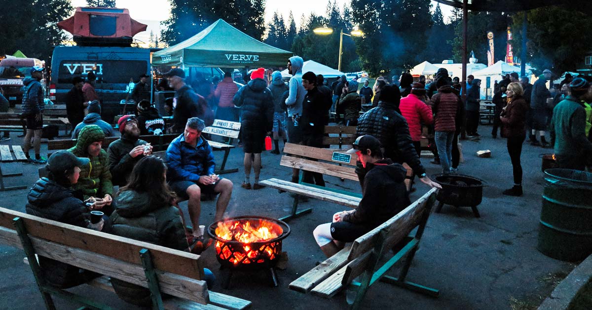 Crowd of people at the festival around a fire pit with food trucks in the background